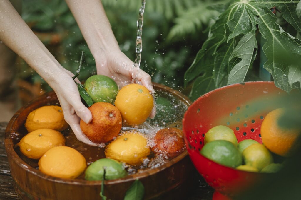 Woman washing fresh fruits in tropical orchard