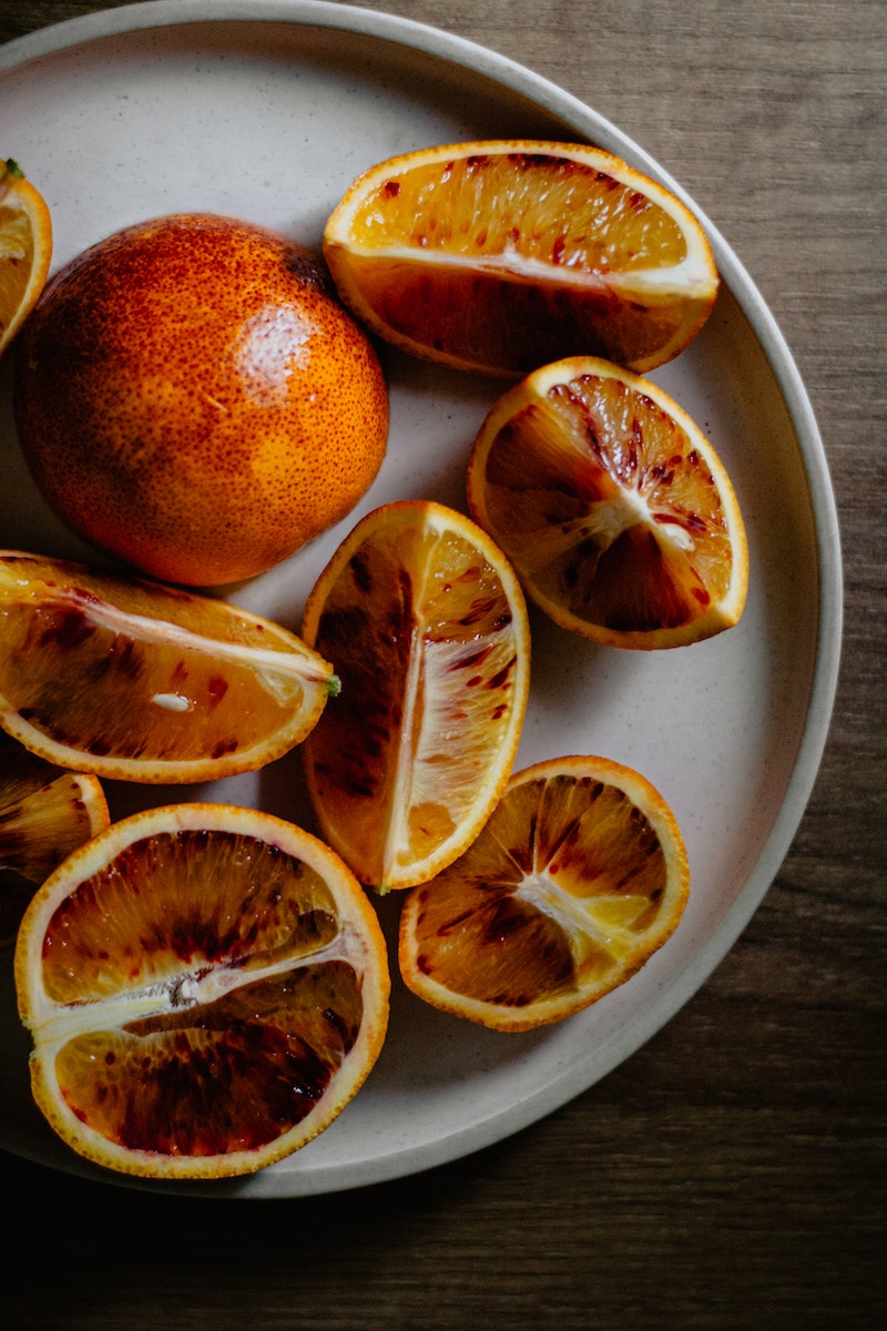 Cut ripe juicy oranges on ceramic plate