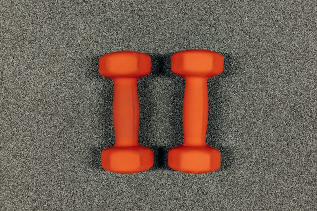 Pair Of Orange Dumbbells On Gray Surface