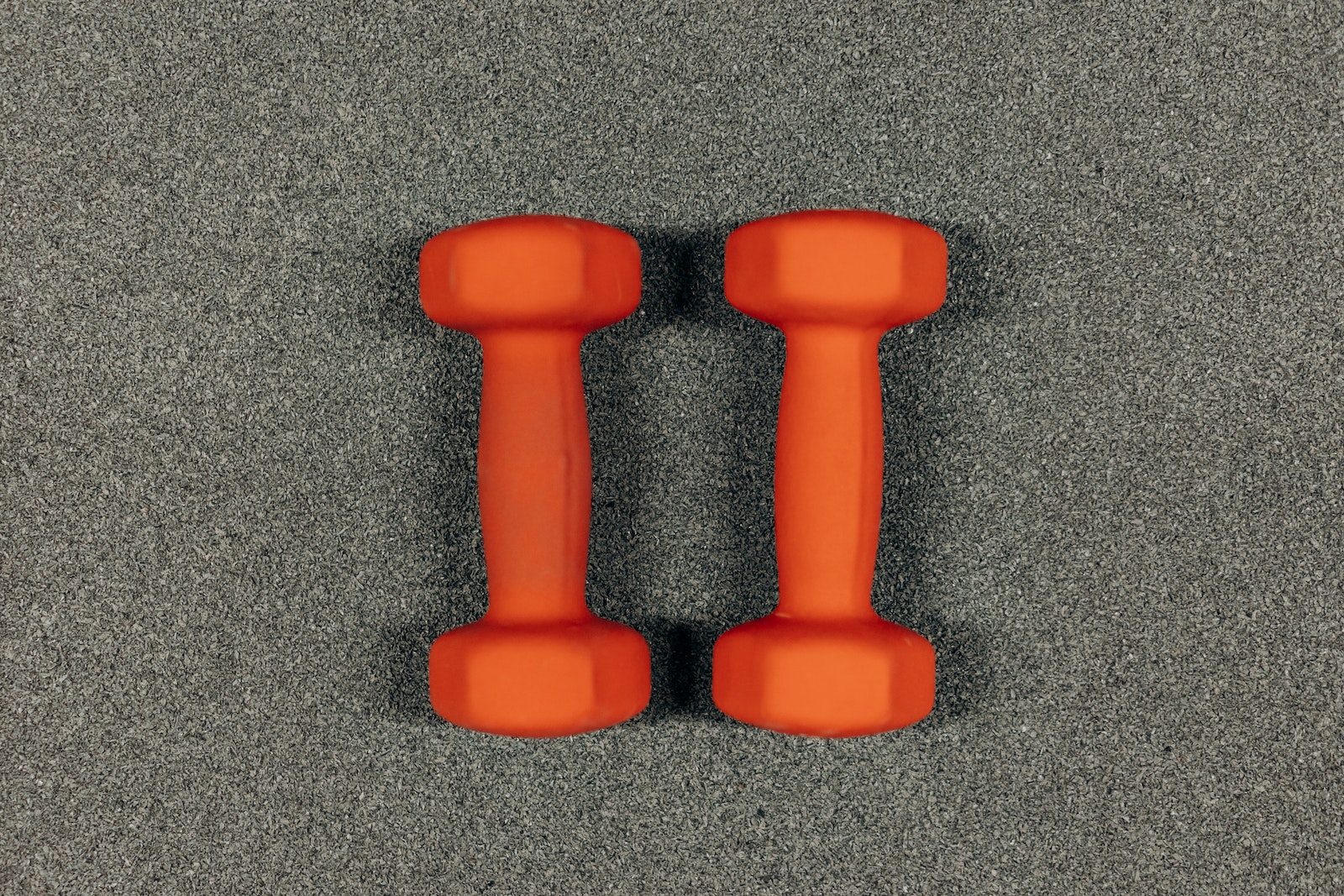 Pair Of Orange Dumbbells On Gray Surface